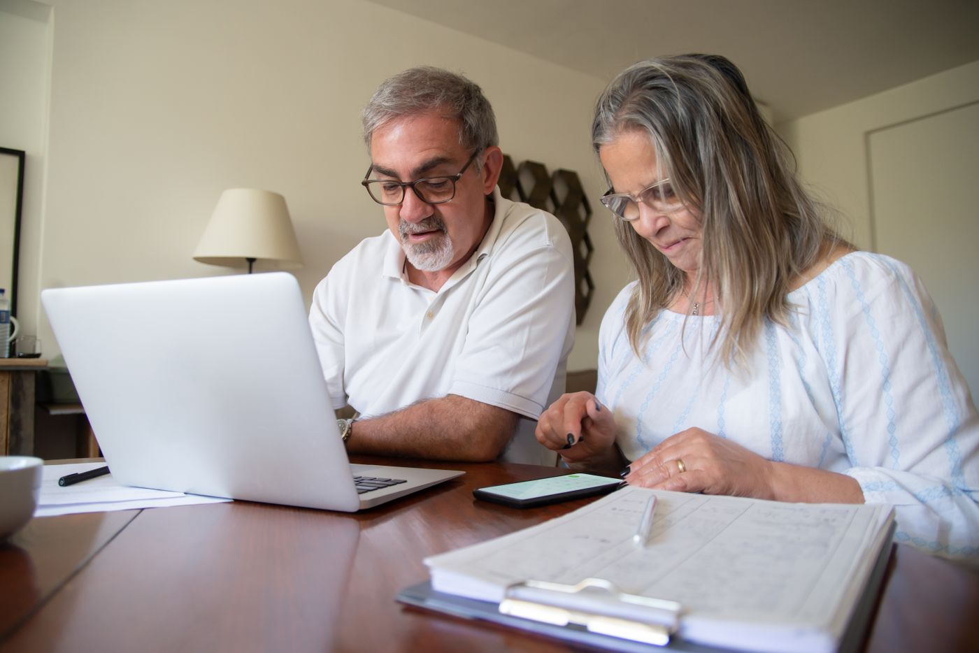 A senior couple reviewing paperwork beside a laptop at home